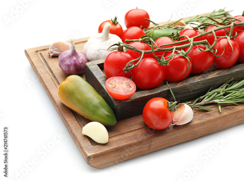 Wooden board with fresh cherry tomatoes, vegetables and rosemary on white background