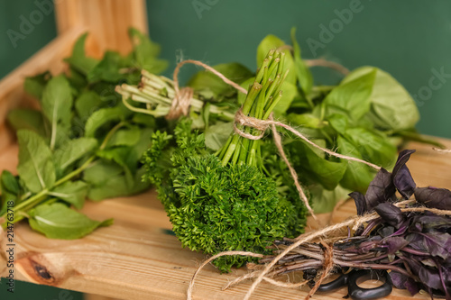 Fresh herbs on wooden shelf near color wall