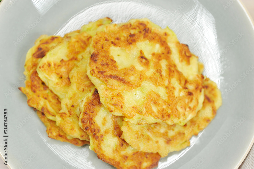 Small pancakes from a zucchini on a plate. The image occupies the entire frame space. Close-up. Macro photography. View from above.