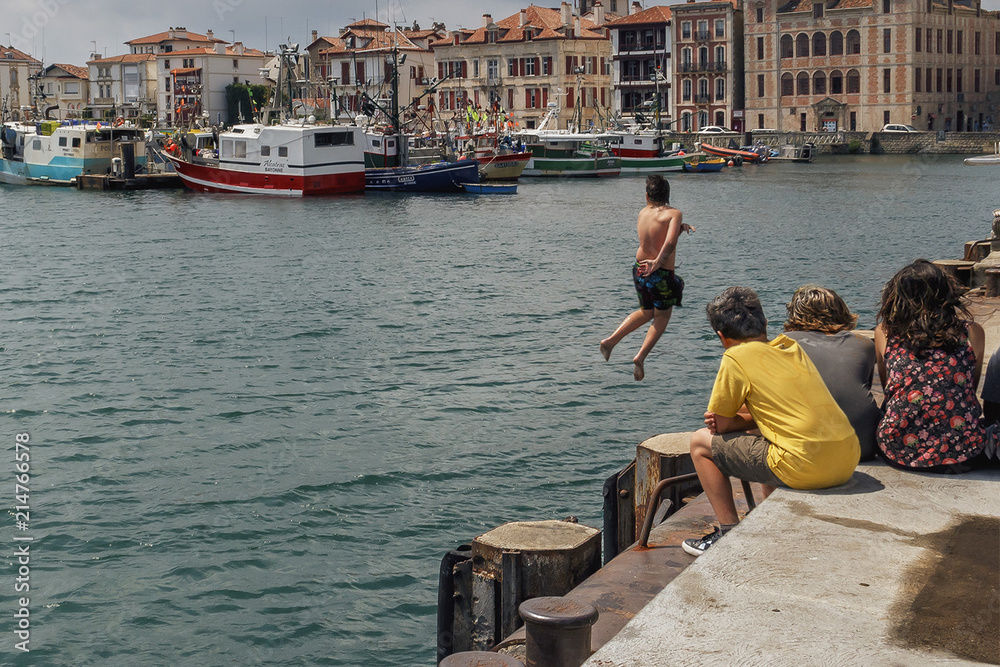 Bayonne, France - June 25, 2014 - a group of children watching a boy jump from a pier into the sea