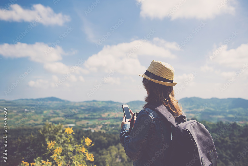 Young asian woman standing and holding smartphone alone outdoor with wild forest mountains on background Travel Lifestyle and survival concept rear view