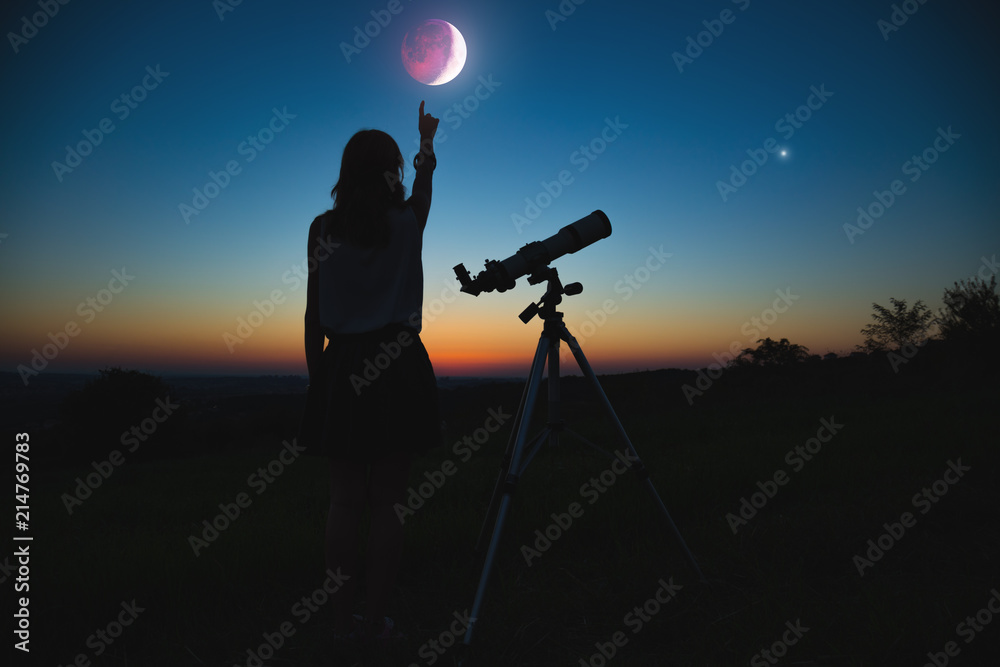 Obraz premium Girl looking at lunar eclipse through a telescope. My astronomy work.