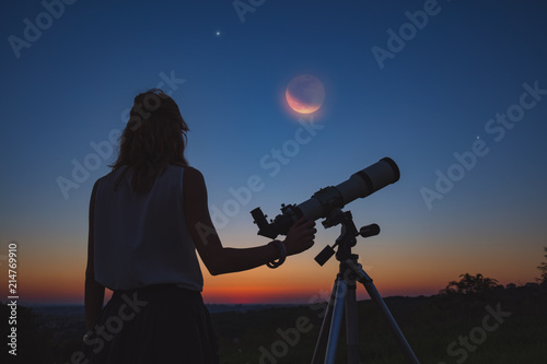 Girl looking at lunar eclipse through a telescope. My astronomy work. photo