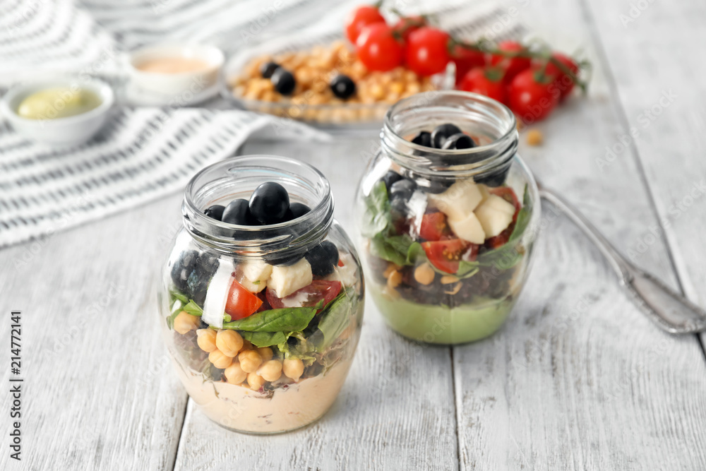 Delicious vegetable salad in jars on wooden table Delicious vegetable salad in jars on wooden table