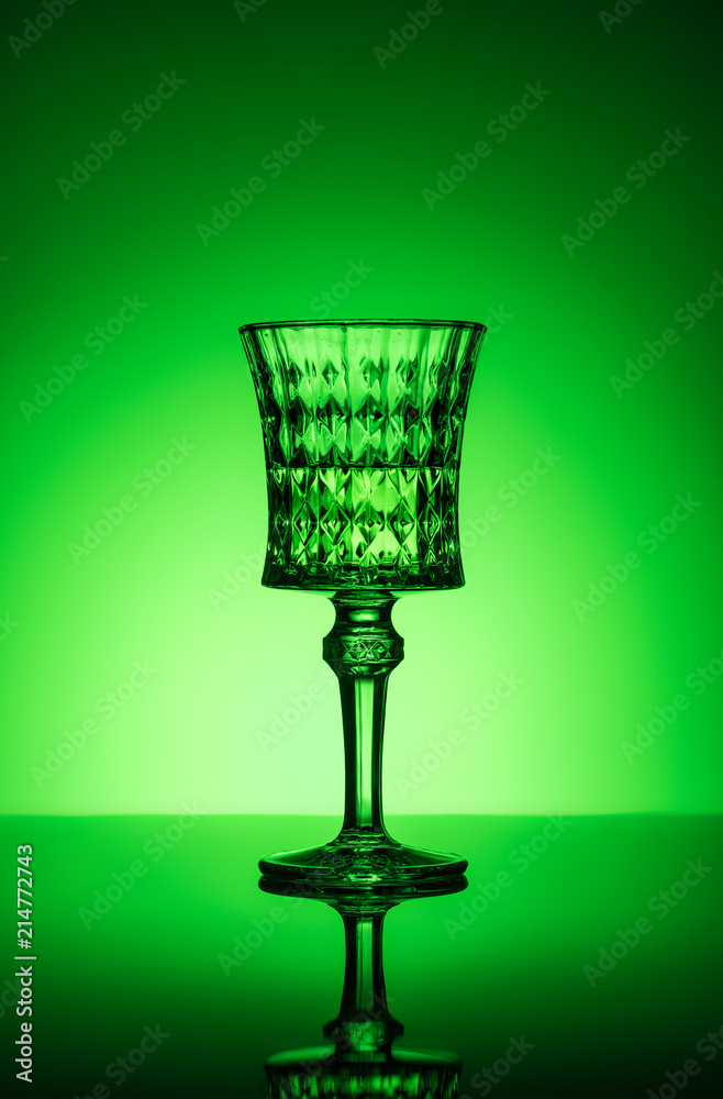 crystal glass of absinthe on reflective surface and dark green background crystal glass of absinthe on reflective surface and dark green background