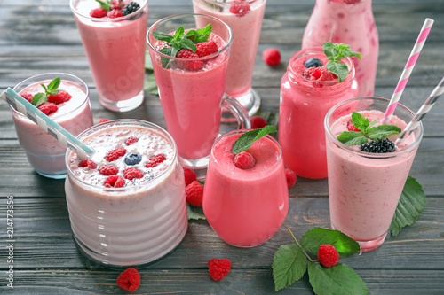 Different glasses with tasty raspberry smoothie on wooden table