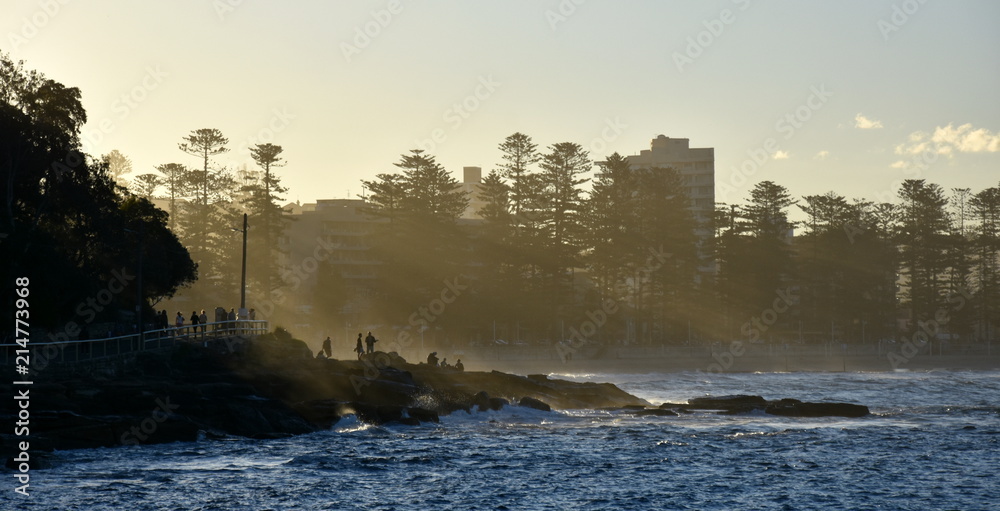 Fog Creeping in at Manly beach. People enjoy the sunset and last sunbeams on the rocks.