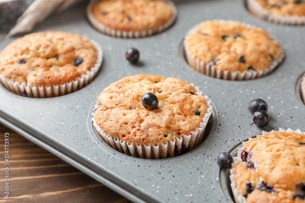 Tasty blueberry muffins in baking tin, closeup