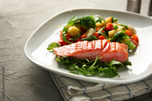 Plate with fresh salad and fish on light table, closeup