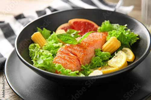 Bowl with fresh salad and fish on table, closeup