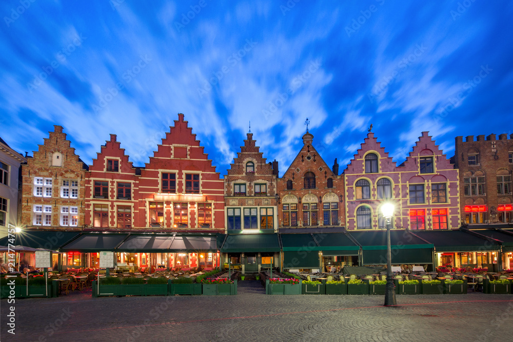 Fototapeta premium Typowe domy w kolorze flamandzkim na Grote Markt lub Rynku w centrum Brugii podczas niebieskiej wieczornej godziny, Belgia