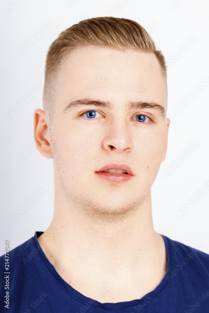 Young man in blue shirt poses in studio, close up portrait Young man in blue shirt poses in studio, close up portrait
