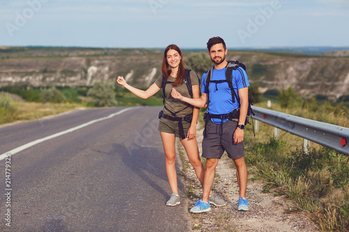 The guy and the girl are hitchhiking along the road.
