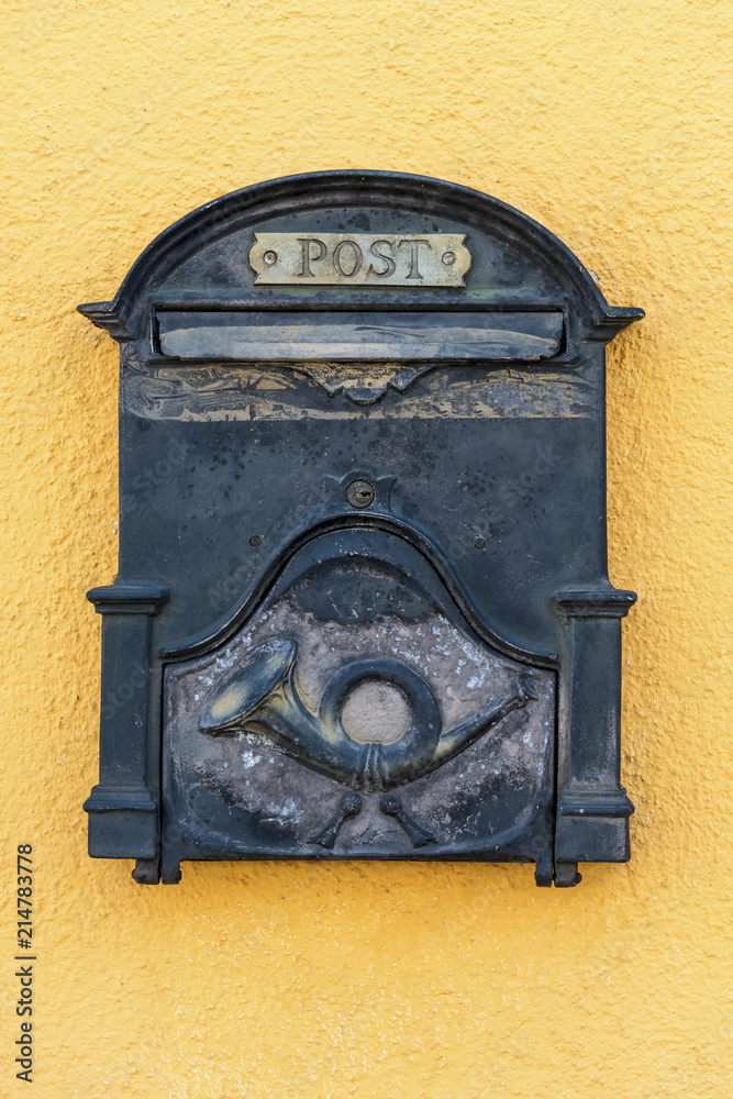 Ein alter nostalgischer Metall Postkasten auf einer gelben Hauswand