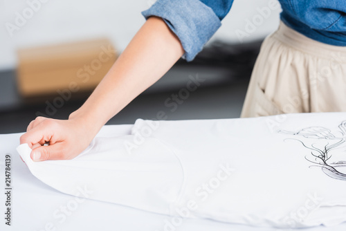 cropped image of female designer putting white t-shirt with print on ironing board © LIGHTFIELD STUDIOS