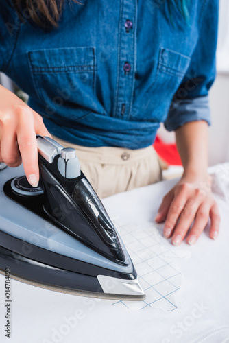 cropped image of female designer ironing white t-shirt with print