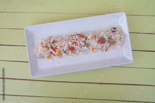 rice salad in a white tray on a green wooden table seen from above