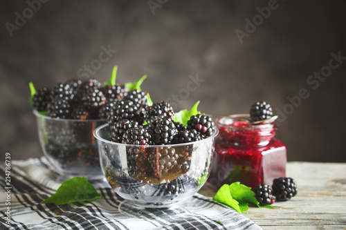 Ripe blackberry and blackberry jam on a wooden table. Dark background.