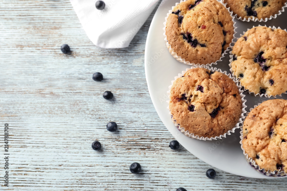 Plate with tasty blueberry muffins on wooden background Plate with tasty blueberry muffins on wooden background