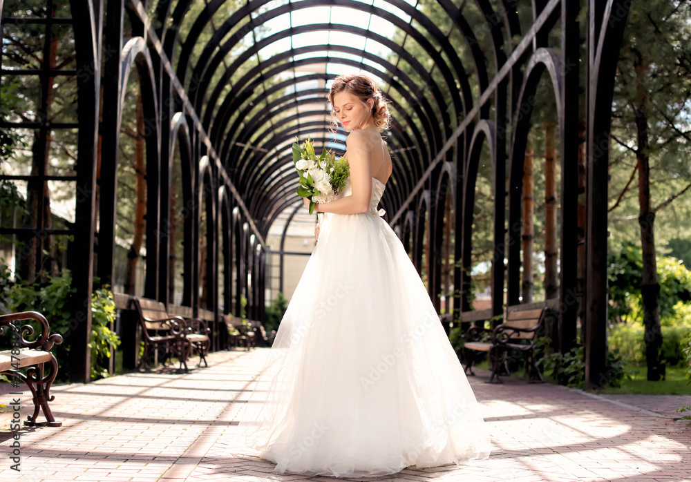 Obraz premium Beautiful young bride with wedding bouquet outdoors