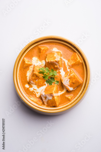 Paneer Butter Masala also known as Panir makhani or makhanwala. served in a ceramic or terracotta bowl with fresh cream and coriander. Isolated over colourful moody background. selective focus