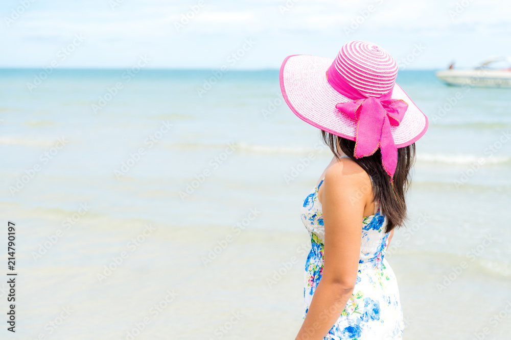 Beautiful woman wearing hat beach and sunglasses stand on hands over sandy beach, green sea and blue sky background for summer holiday and vacation concept.