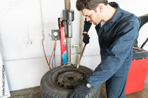 Repairman Removing Tire From Rim On Machine At Garage