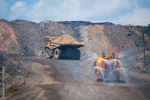 Heavy truck pours the road with water in the iron ore quarry. Dust removal, protection of the environment. Irrigation of the road from dust	