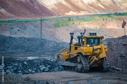 A yellow bulldozer builds a road in an iron ore quarry. 