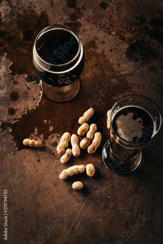 top view of table set with peanuts and mugs of beer on rust surface