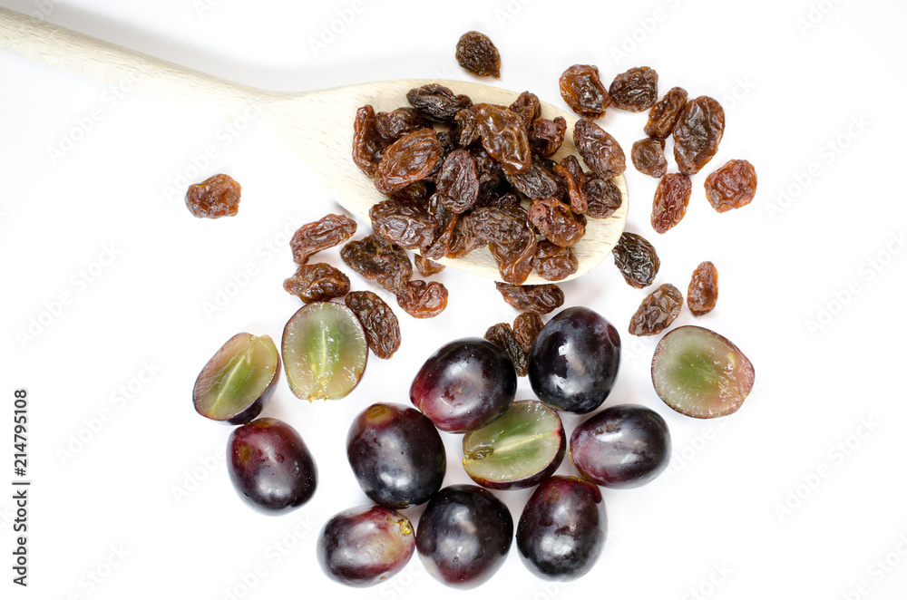 Obraz premium raisins on a wooden spoon on white background with grapes