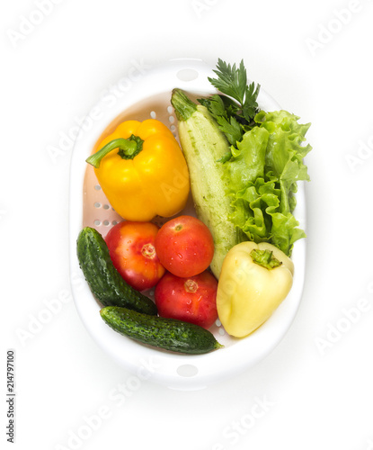 Fresh vegetables in a colander bowl on a white background