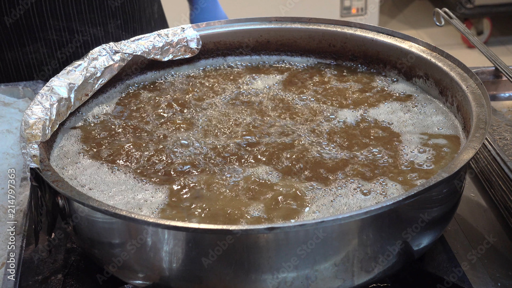 The cook puts meat balls in boiling oil. The cook puts meat balls in boiling oil.