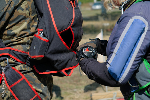 sports parachutists check each other's equipment with an altimeter on his hand, a summer sunny day