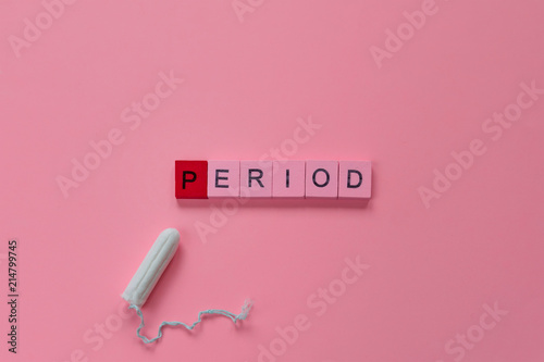 menstruation concept: word period spelled with pink letters on pink background with a tampon photo