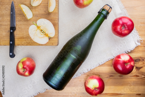 Flat lay with icy cooled corked cidre bottle on rustic wooden table. Top view of premium cider and locally grown organic apples photo