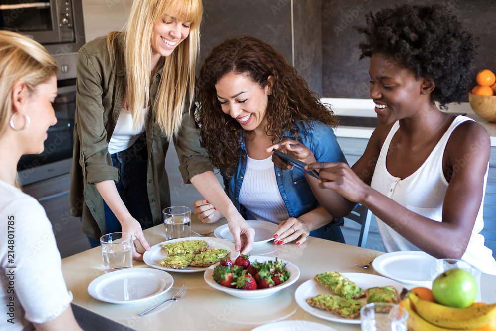 Group of friends laughing while eating healthy food at home. Group of friends laughing while eating healthy food at home.