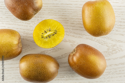 Group of five whole one half of fresh golden brown kiwi fruit sungold variety flatlay on grey wood