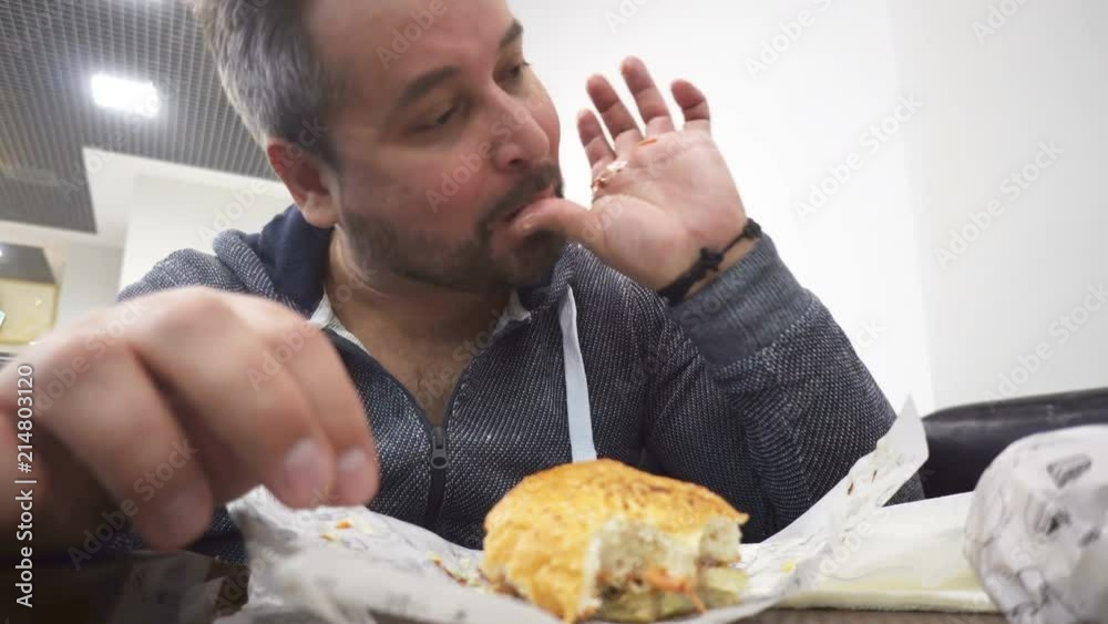 Hangry man eating big hamburger in fast food cafe Hangry man eating big hamburger in fast food cafe