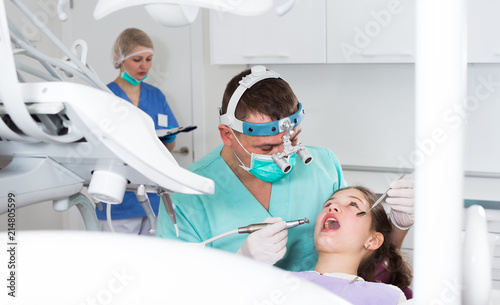 Male dentist performing treatment to girl