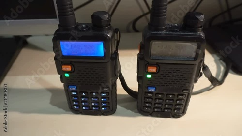 Two black handled portable walkie- talkie radio transmitter working and flashing in the dark