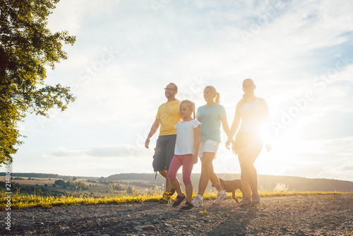 Family having an evening walk with the dog in rural setting