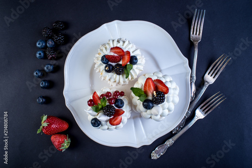 Delicate white meringues with fresh berries on the plate. Dessert Pavlova close-up. Wedding cake.