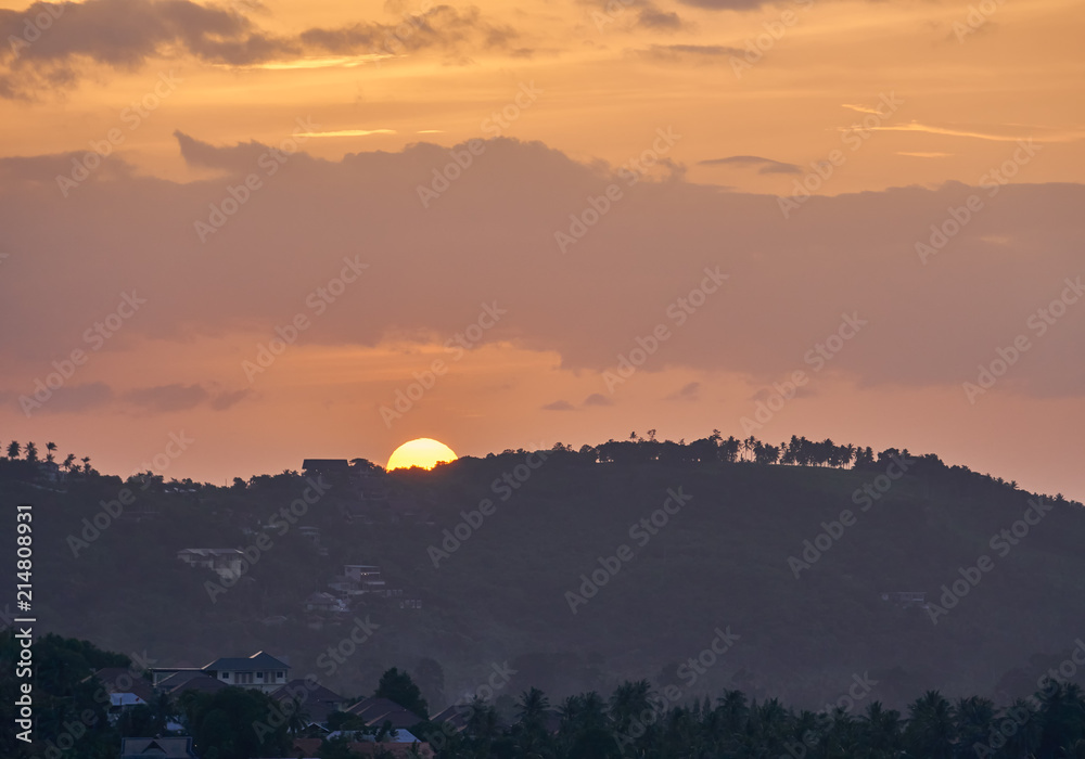 The village in the valley against the background of the sun setting over mountains             
