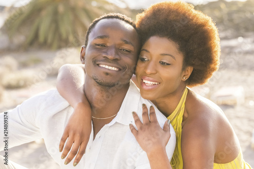 happy beautiful black race african couple in love or friendship stay together walking hugged with big smilies under the sunlight of the summer in vacation or lifestyle in their city. relationship