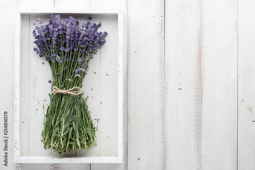 Fototapeta premium Piękny bukiet kwiatów lawendy w białej drewnianej tacy na deskach, widok z góry