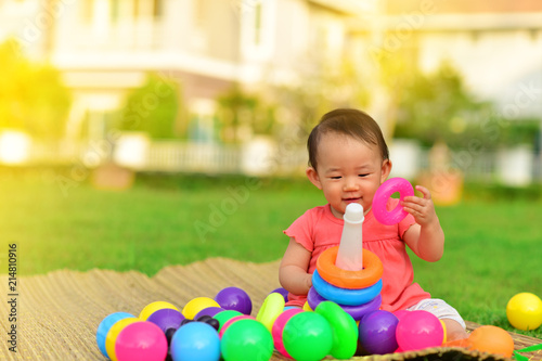 Cute Asian baby playing with toys in playground
