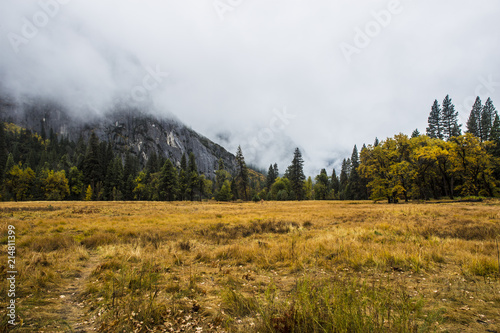 open field recessed behind large mountains in autumn