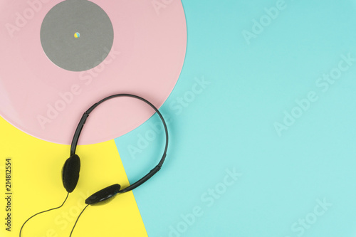 top view of a pink long play vinyl record or LP with a black on-ear headphone on the yellow and blue background photo