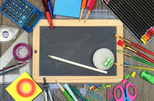 Back to school concept: office and school supplies with a blackboard on a wooden background.